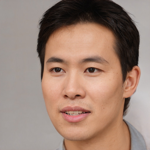 Joyful asian young-adult male with short  brown hair and brown eyes