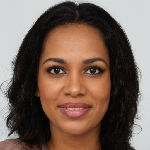 Joyful black young-adult female with long  brown hair and brown eyes