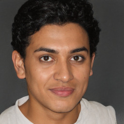 Joyful latino young-adult male with short  brown hair and brown eyes