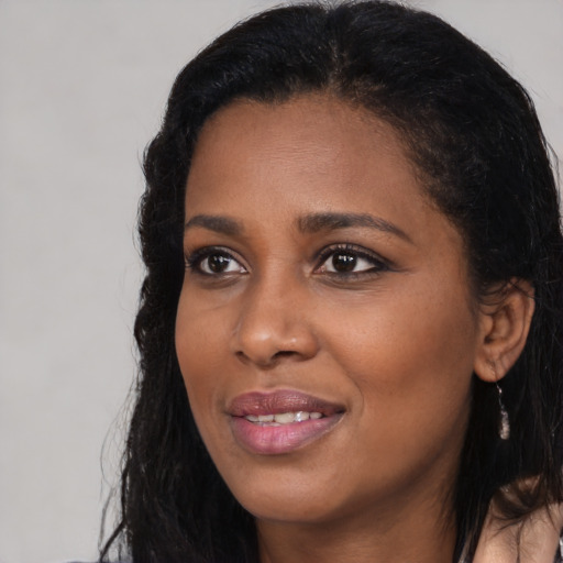 Joyful black young-adult female with long  black hair and brown eyes