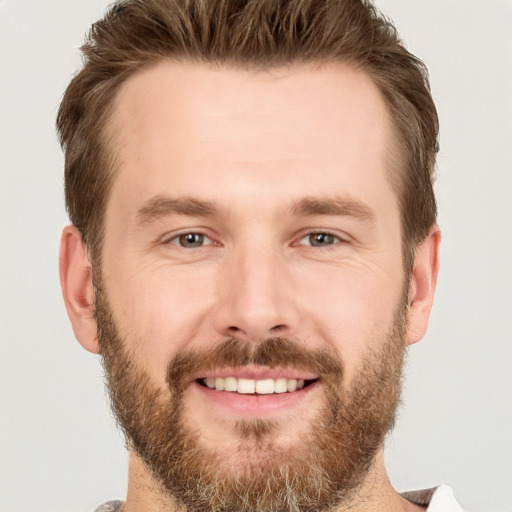 Joyful white young-adult male with short  brown hair and grey eyes