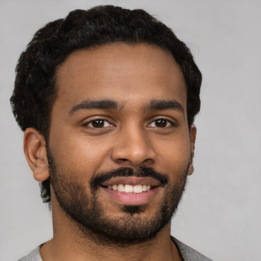 Joyful black young-adult male with short  brown hair and brown eyes