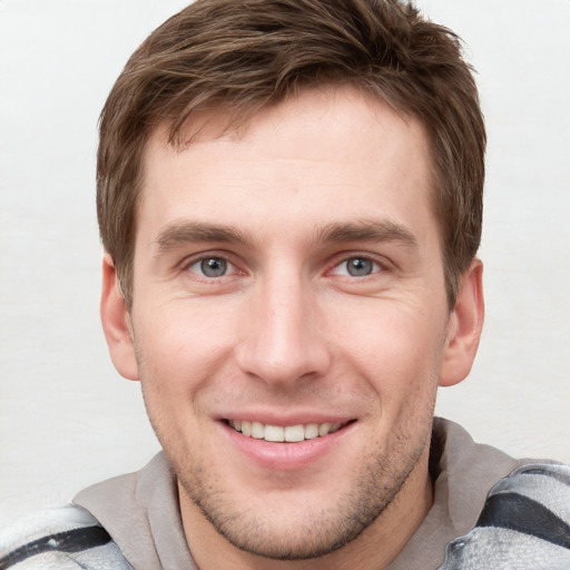 Joyful white young-adult male with short  brown hair and grey eyes