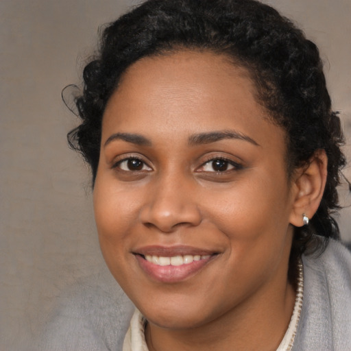 Joyful black young-adult female with long  brown hair and brown eyes