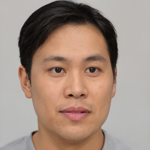 Joyful asian young-adult male with short  brown hair and brown eyes