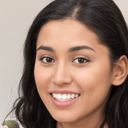 Joyful latino young-adult female with long  brown hair and brown eyes