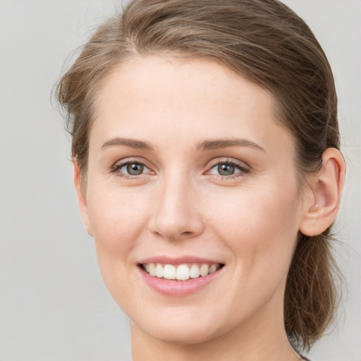 Joyful white young-adult female with medium  brown hair and grey eyes