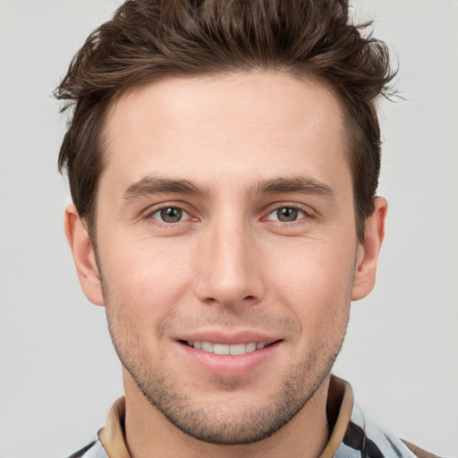 Joyful white young-adult male with short  brown hair and grey eyes