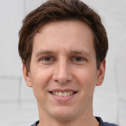 Joyful white young-adult male with short  brown hair and grey eyes