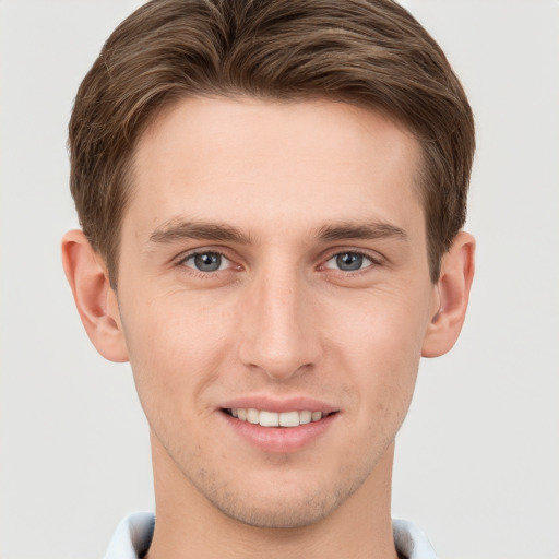 Joyful white young-adult male with short  brown hair and grey eyes