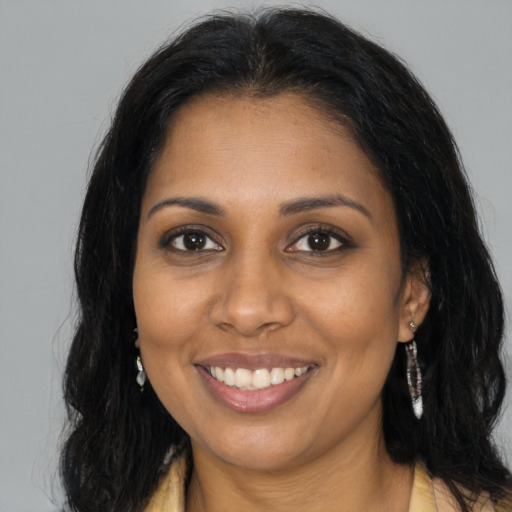 Joyful black young-adult female with long  brown hair and brown eyes