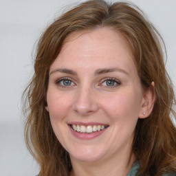 Joyful white young-adult female with long  brown hair and blue eyes