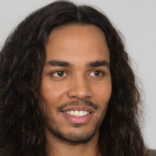 Joyful latino young-adult male with long  brown hair and brown eyes