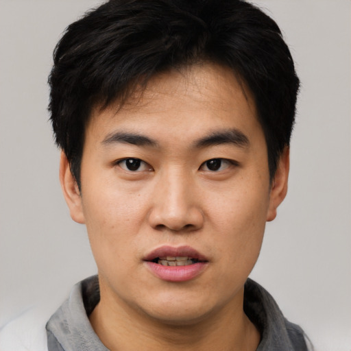 Joyful asian young-adult male with short  black hair and brown eyes