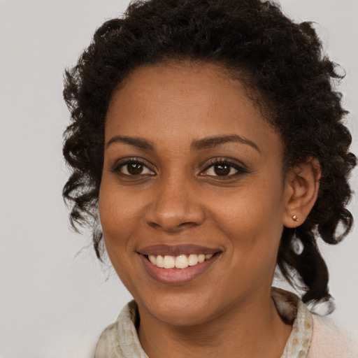 Joyful black young-adult female with long  brown hair and brown eyes