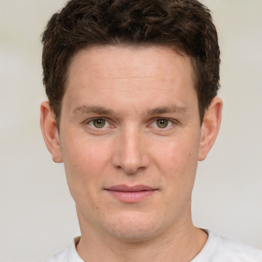 Joyful white young-adult male with short  brown hair and green eyes