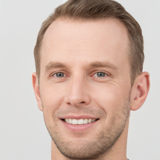 Joyful white young-adult male with short  brown hair and grey eyes