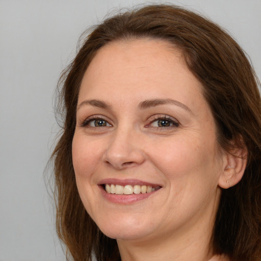 Joyful white adult female with long  brown hair and grey eyes