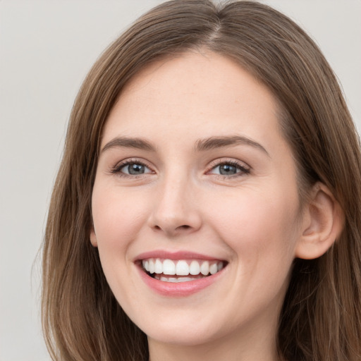 Joyful white young-adult female with long  brown hair and grey eyes