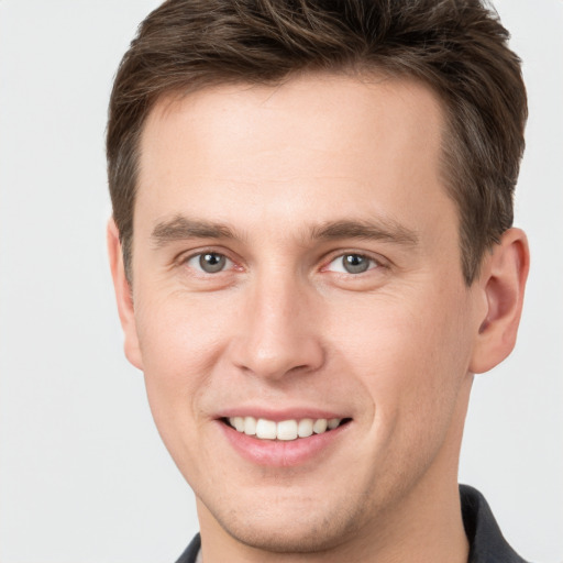 Joyful white young-adult male with short  brown hair and grey eyes