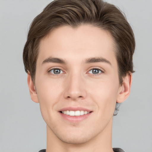 Joyful white young-adult male with short  brown hair and grey eyes