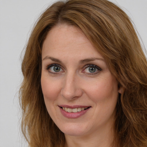 Joyful white adult female with long  brown hair and green eyes