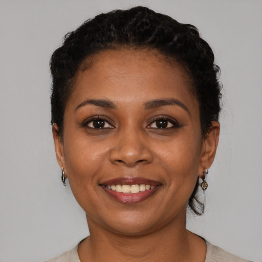 Joyful black young-adult female with short  black hair and brown eyes