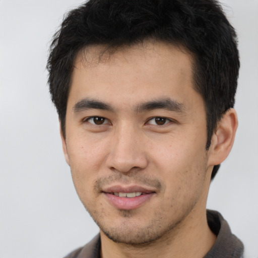 Joyful asian young-adult male with short  brown hair and brown eyes