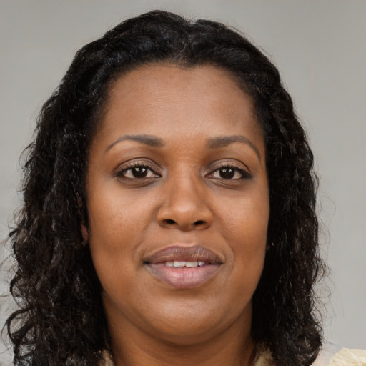 Joyful black young-adult female with long  brown hair and brown eyes