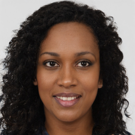 Joyful black young-adult female with long  black hair and brown eyes
