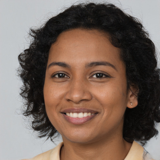 Joyful black young-adult female with long  brown hair and brown eyes