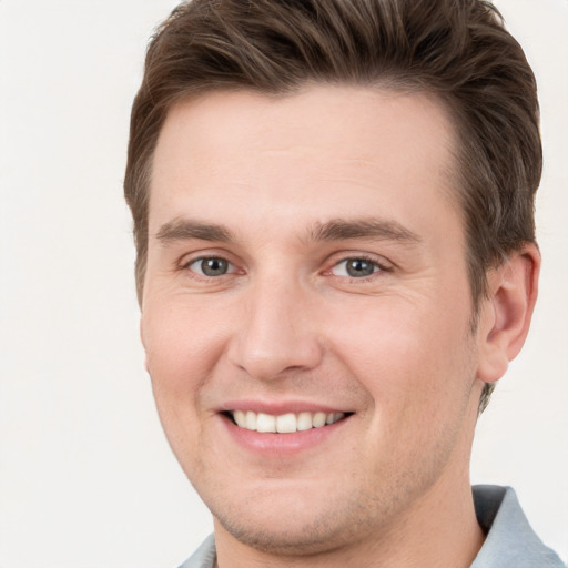 Joyful white young-adult male with short  brown hair and grey eyes