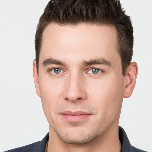 Joyful white young-adult male with short  brown hair and grey eyes