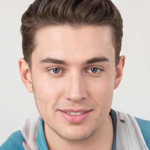 Joyful white young-adult male with short  brown hair and grey eyes