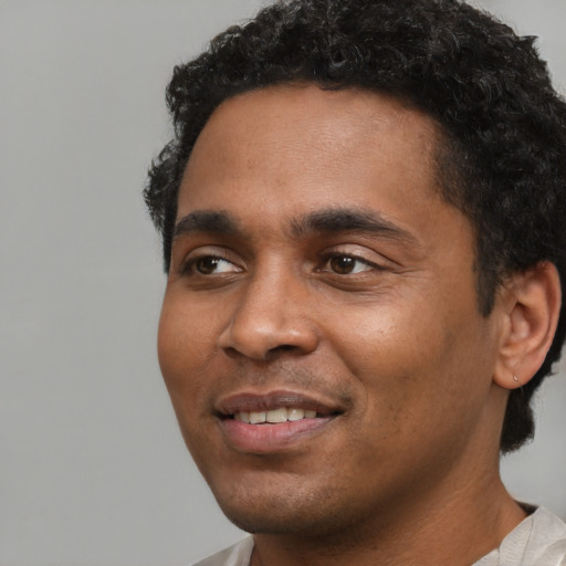 Joyful black young-adult male with short  black hair and brown eyes