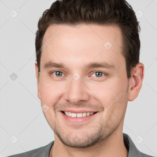 Joyful white young-adult male with short  brown hair and grey eyes