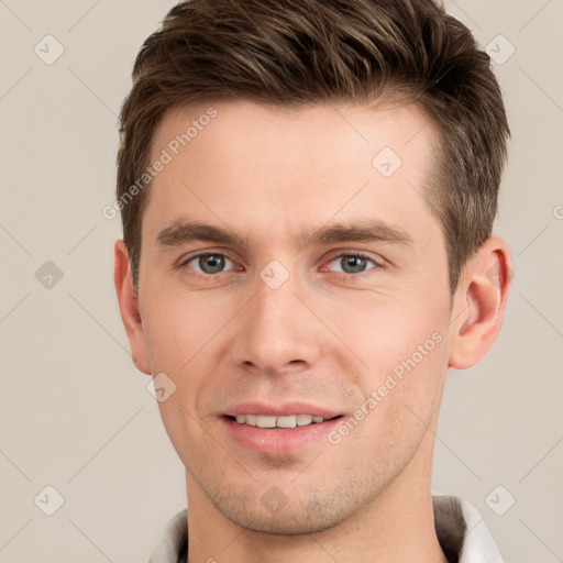 Joyful white young-adult male with short  brown hair and grey eyes