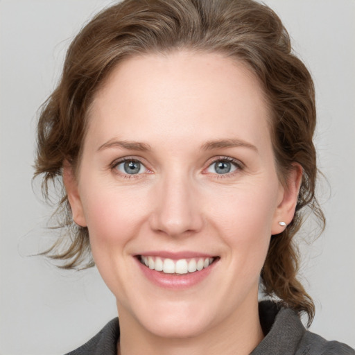 Joyful white young-adult female with medium  brown hair and grey eyes