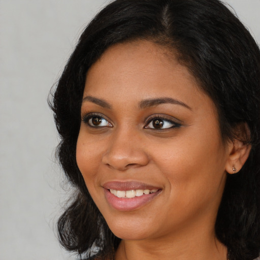 Joyful black young-adult female with long  brown hair and brown eyes