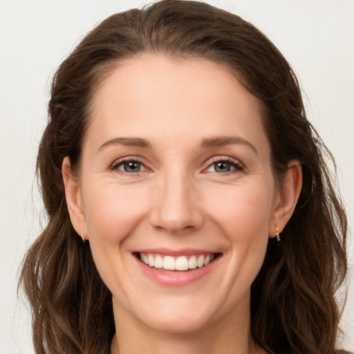 Joyful white young-adult female with long  brown hair and grey eyes