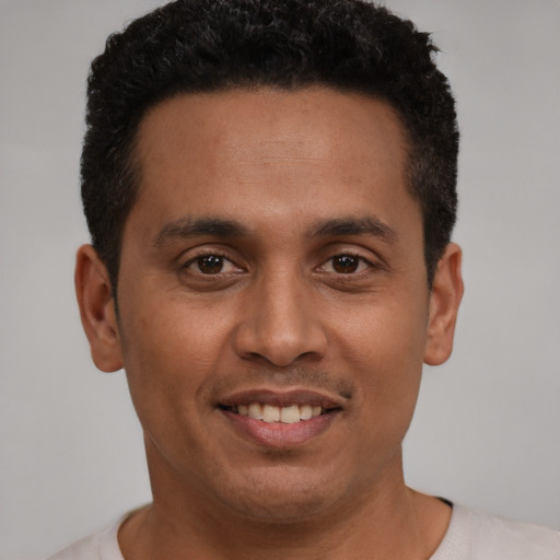 Joyful latino young-adult male with short  black hair and brown eyes