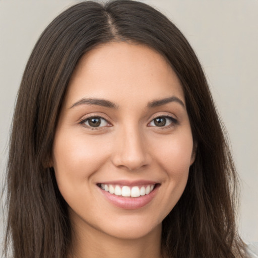 Joyful white young-adult female with long  brown hair and brown eyes