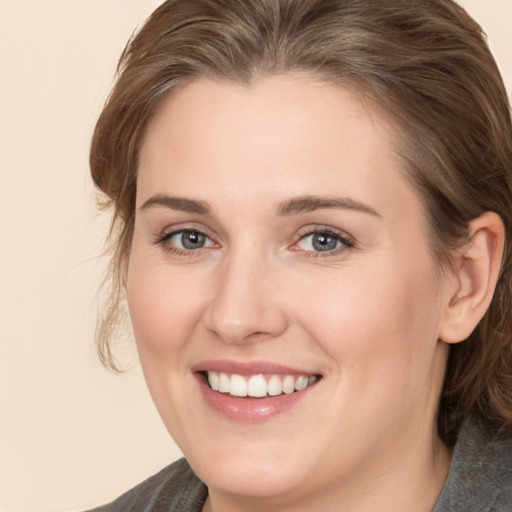 Joyful white young-adult female with medium  brown hair and grey eyes