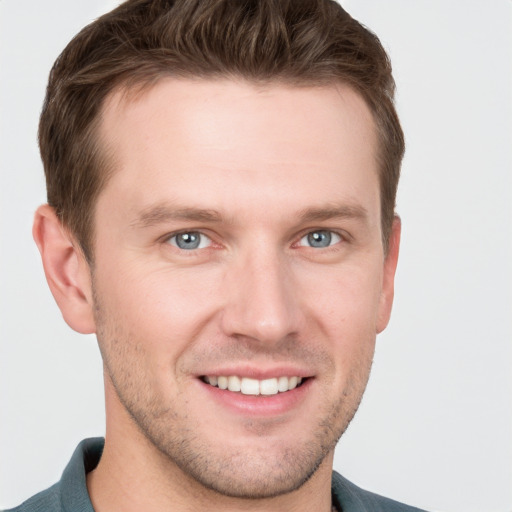 Joyful white young-adult male with short  brown hair and grey eyes