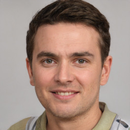 Joyful white young-adult male with short  brown hair and grey eyes