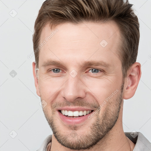 Joyful white young-adult male with short  brown hair and grey eyes