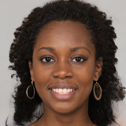 Joyful black young-adult female with long  black hair and brown eyes