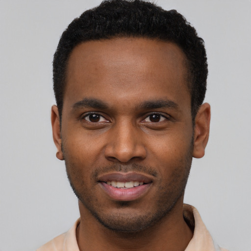 Joyful black young-adult male with short  brown hair and brown eyes