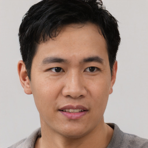 Joyful asian young-adult male with short  black hair and brown eyes