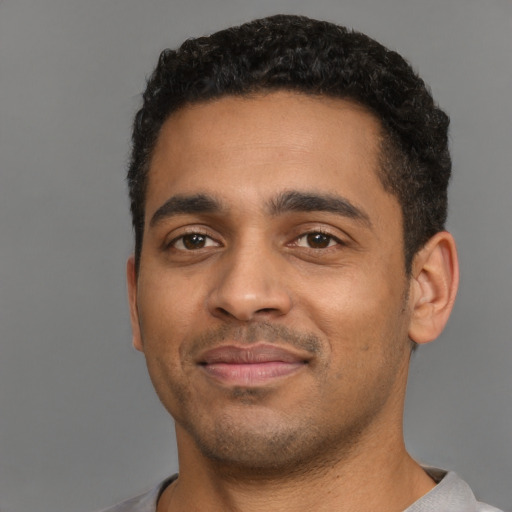 Joyful black young-adult male with short  black hair and brown eyes